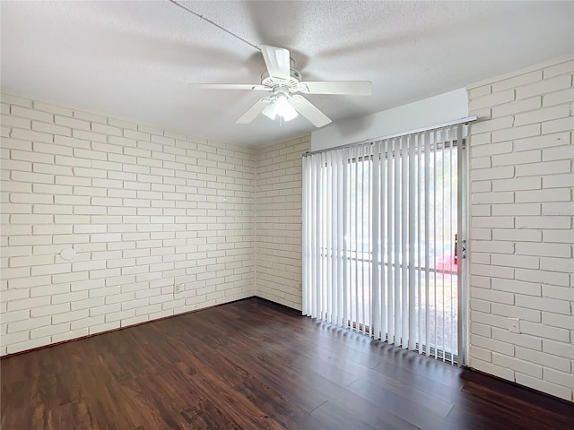 spare room featuring dark hardwood / wood-style flooring and brick wall