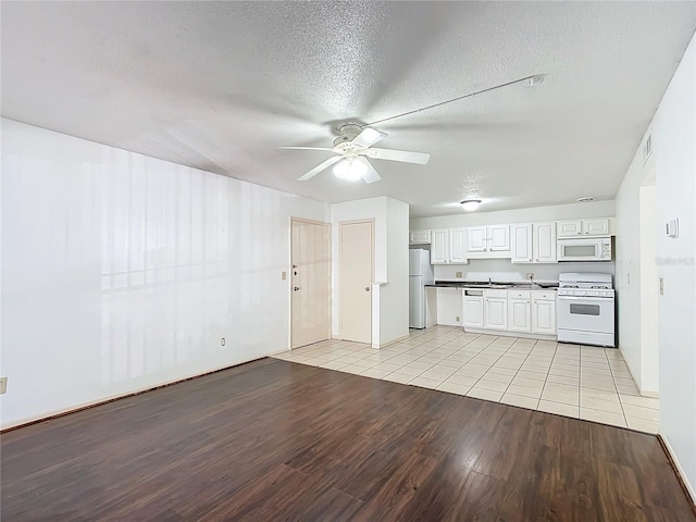 kitchen with white appliances, a textured ceiling, white cabinetry, light hardwood / wood-style floors, and ceiling fan