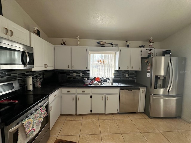 kitchen featuring tasteful backsplash, light tile patterned floors, stainless steel appliances, and white cabinetry