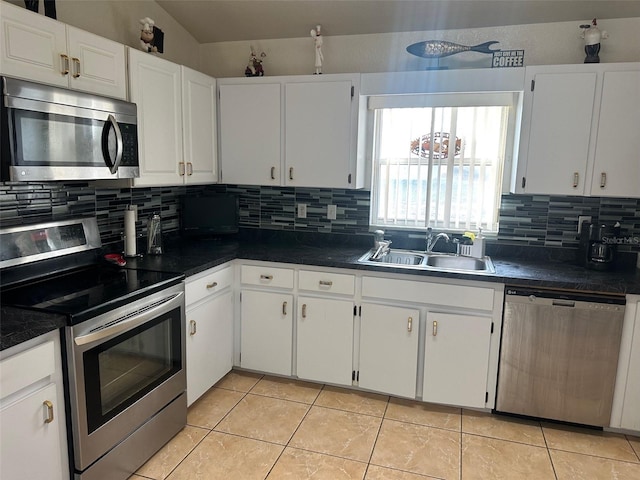 kitchen with light tile patterned floors, sink, stainless steel appliances, and white cabinetry