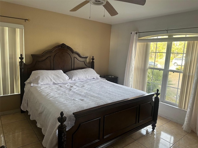 bedroom with ceiling fan, light tile patterned floors, and multiple windows