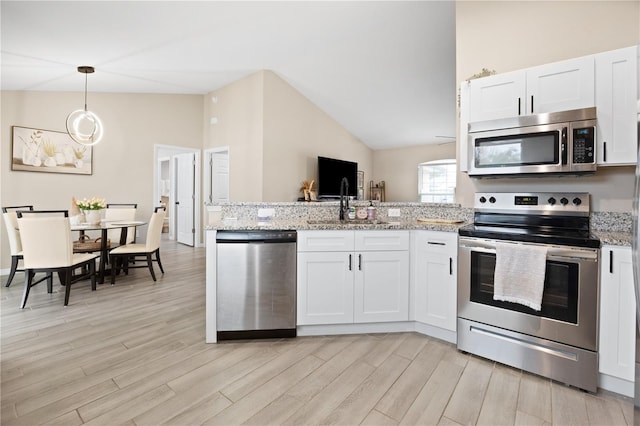 kitchen with pendant lighting, sink, white cabinetry, light stone countertops, and stainless steel appliances