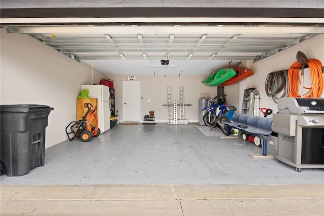 garage with white refrigerator, water heater, and a garage door opener