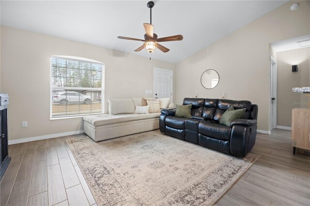 living area with a ceiling fan, wood finished floors, baseboards, and vaulted ceiling