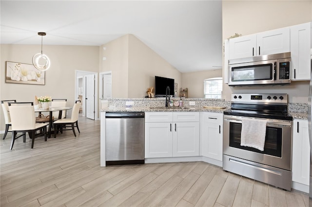 kitchen with appliances with stainless steel finishes, lofted ceiling, a peninsula, a sink, and light wood-style flooring