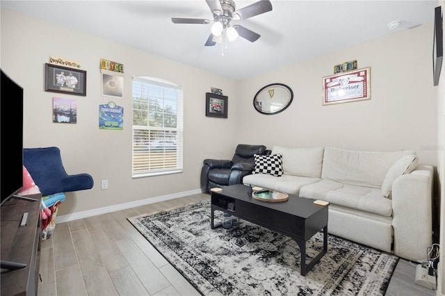 living room featuring ceiling fan, light wood-style floors, and baseboards