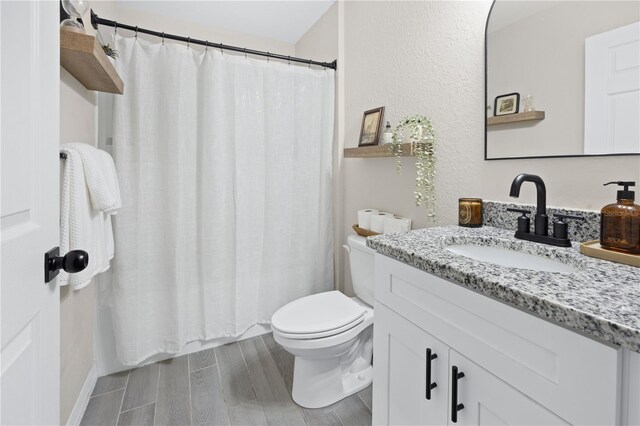 bathroom with toilet, wood finished floors, vanity, and a shower with shower curtain