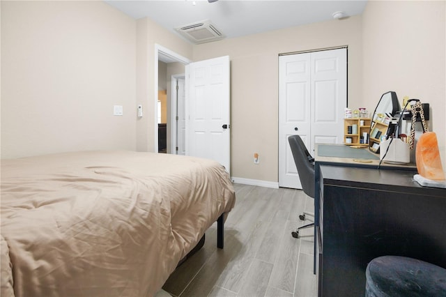 bedroom with light wood-style floors, a closet, an office area, and baseboards