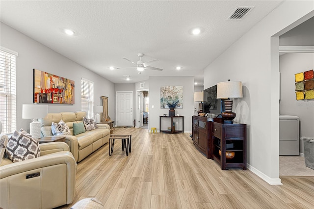 living room with washer / dryer, ceiling fan, a textured ceiling, and light wood-type flooring