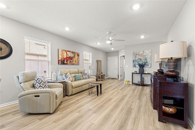 living room with a textured ceiling, light hardwood / wood-style flooring, and a healthy amount of sunlight