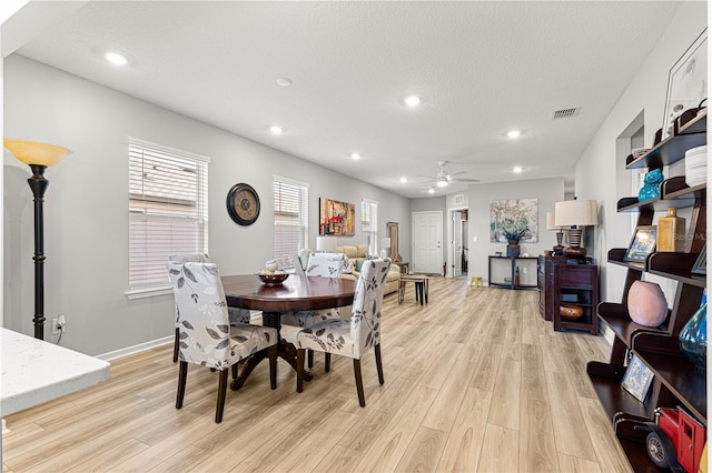 dining room with light wood-type flooring, ceiling fan, and a textured ceiling