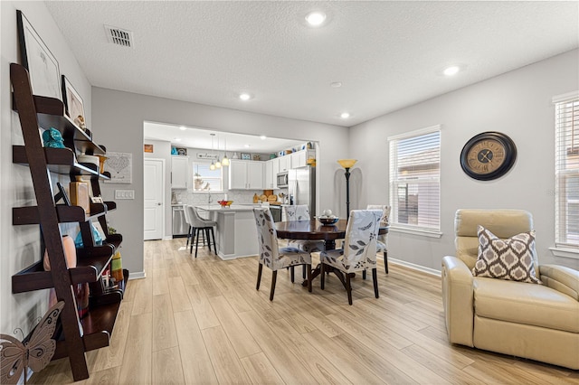 dining area with a textured ceiling and light wood-type flooring