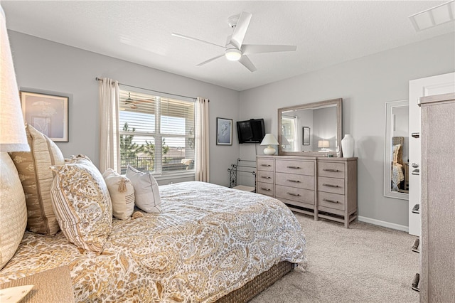 bedroom with ceiling fan, light colored carpet, and a textured ceiling