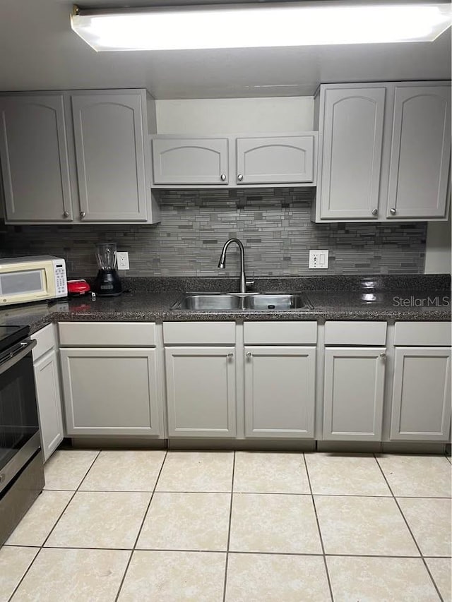 kitchen with sink, electric stove, tasteful backsplash, and light tile patterned flooring