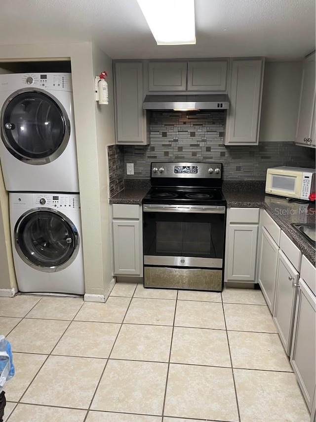 kitchen featuring stacked washer / dryer, light tile patterned floors, gray cabinetry, and stainless steel range with electric stovetop