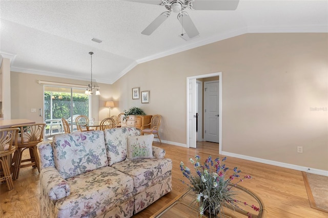 living room with ceiling fan with notable chandelier, ornamental molding, vaulted ceiling, and light hardwood / wood-style flooring