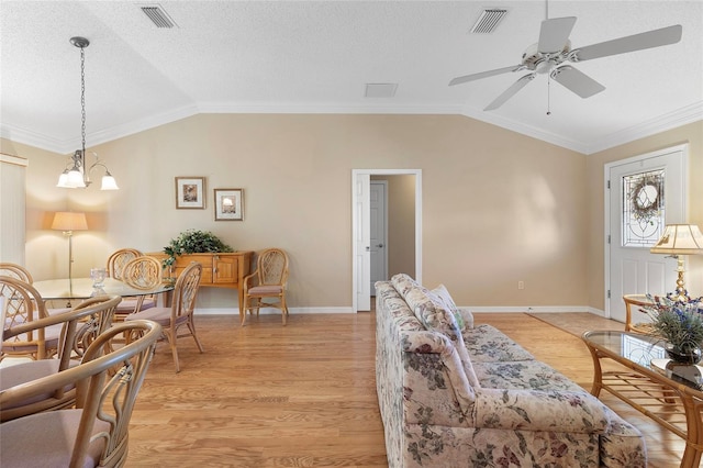 living room featuring crown molding, lofted ceiling, a textured ceiling, and light hardwood / wood-style flooring