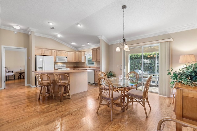 dining area featuring crown molding, plenty of natural light, lofted ceiling, and light wood-type flooring