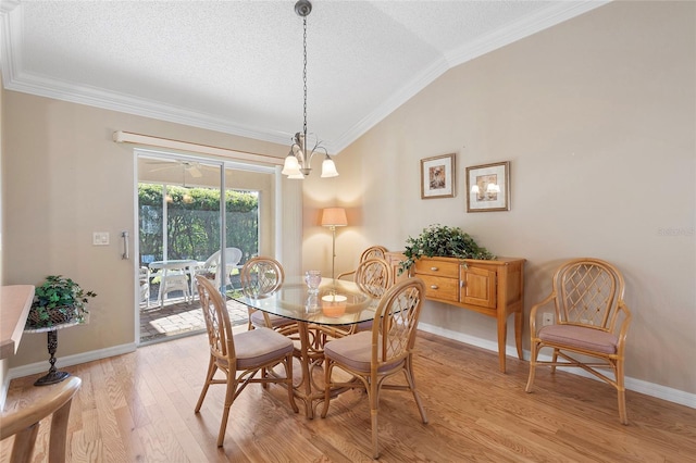 dining space featuring lofted ceiling, crown molding, a chandelier, a textured ceiling, and light wood-type flooring