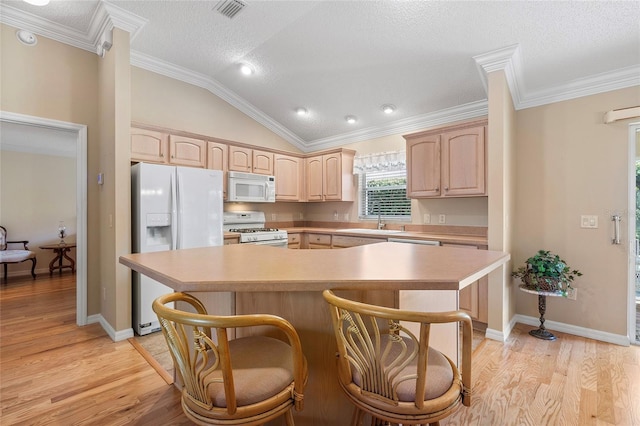 kitchen with white appliances, a center island, a kitchen bar, light brown cabinetry, and vaulted ceiling