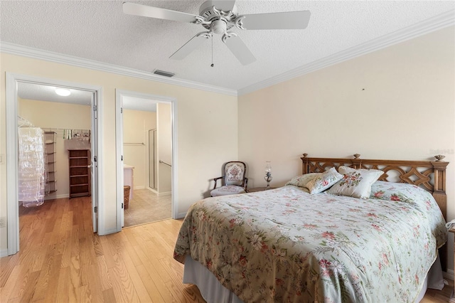 bedroom with crown molding, a textured ceiling, and light hardwood / wood-style floors