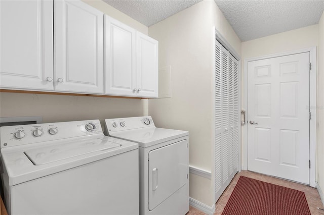 laundry room with light tile patterned flooring, cabinets, washer and dryer, and a textured ceiling