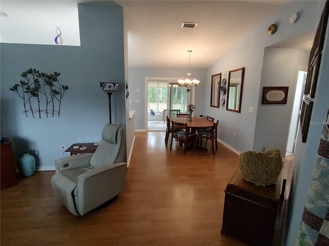 dining area with vaulted ceiling, a chandelier, and hardwood / wood-style flooring