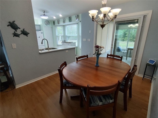 dining area with sink, wood-type flooring, a notable chandelier, and a healthy amount of sunlight