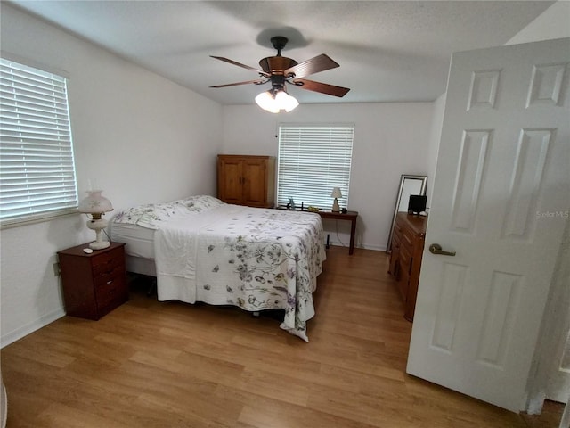 bedroom with ceiling fan, light hardwood / wood-style floors, and multiple windows