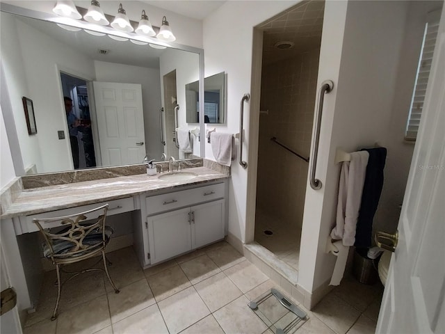 bathroom featuring vanity, tile patterned flooring, and a tile shower