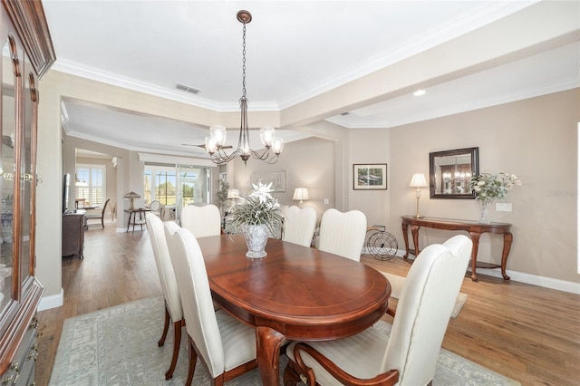 dining room with light wood-type flooring, a chandelier, and ornamental molding