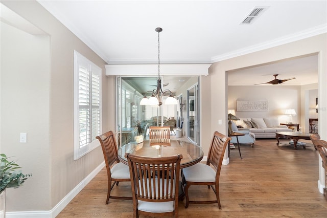 dining area with crown molding, ceiling fan with notable chandelier, and hardwood / wood-style flooring