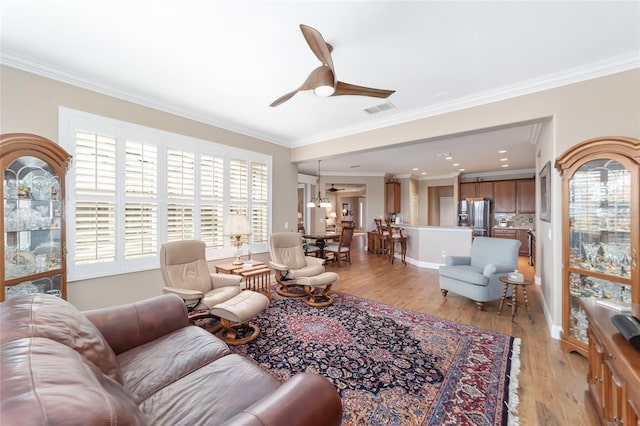 living room featuring light wood-type flooring, ceiling fan, and ornamental molding