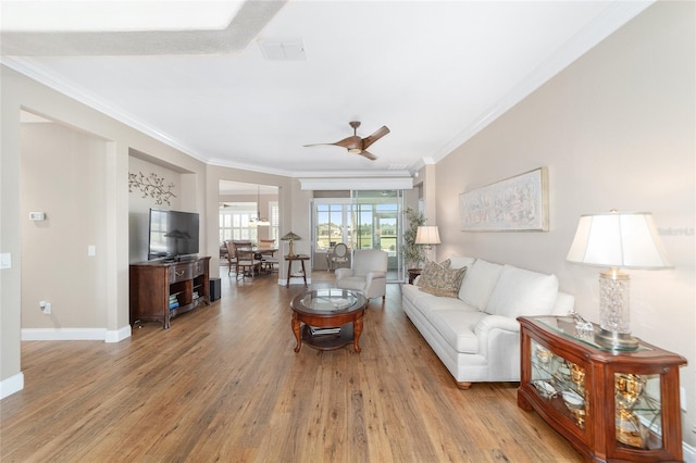 living room with ceiling fan, crown molding, and light hardwood / wood-style floors