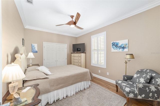 bedroom with ceiling fan, ornamental molding, a closet, and hardwood / wood-style flooring