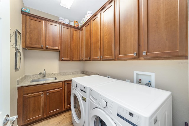 laundry area featuring cabinets, sink, light hardwood / wood-style flooring, and washing machine and dryer