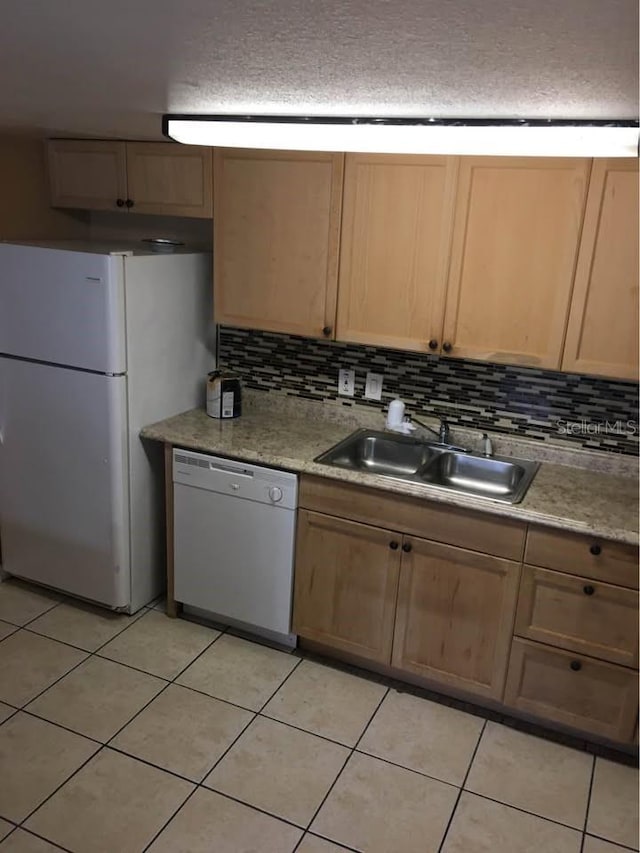 kitchen featuring light brown cabinetry, sink, white appliances, and light tile patterned flooring