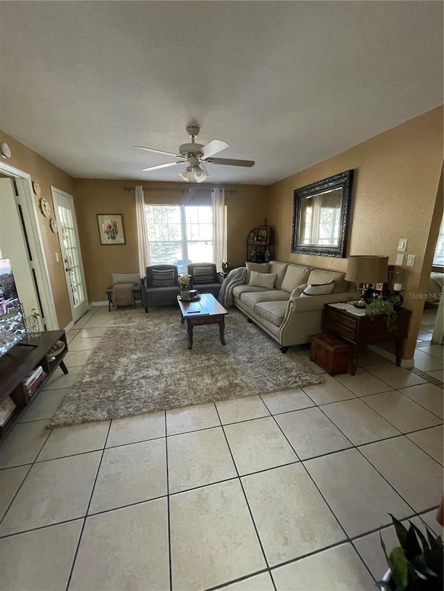 living room featuring ceiling fan, light tile patterned floors, and a textured ceiling