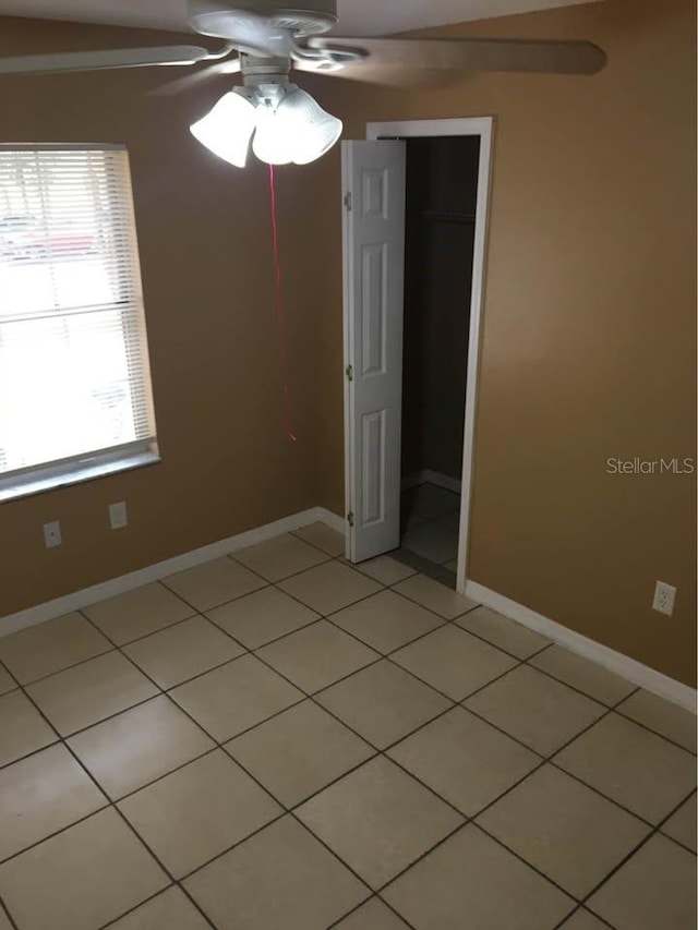 tiled spare room with ceiling fan