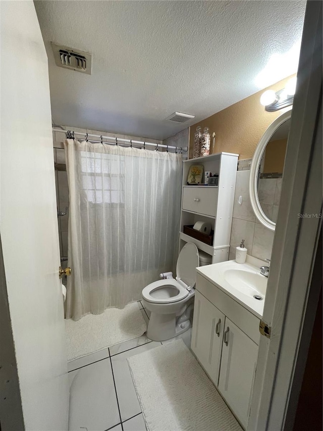 bathroom featuring toilet, a shower with shower curtain, tile patterned floors, a textured ceiling, and vanity