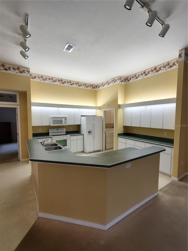 kitchen with white cabinetry, rail lighting, sink, white appliances, and a spacious island