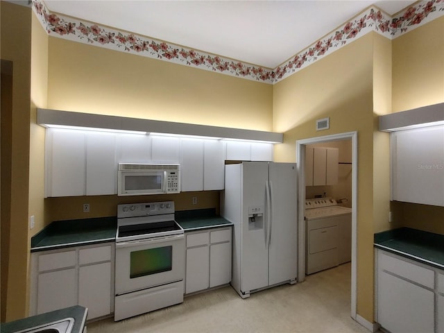 kitchen featuring white cabinetry, washer and clothes dryer, and white appliances