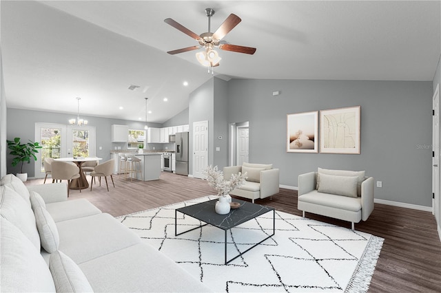 living room with vaulted ceiling, ceiling fan with notable chandelier, and hardwood / wood-style floors