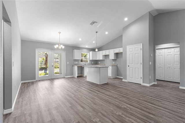 kitchen featuring decorative light fixtures, a kitchen island, hardwood / wood-style flooring, white cabinets, and a chandelier