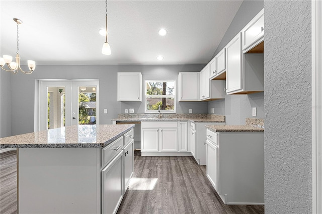 kitchen featuring white cabinets, wood-type flooring, a kitchen island, and pendant lighting