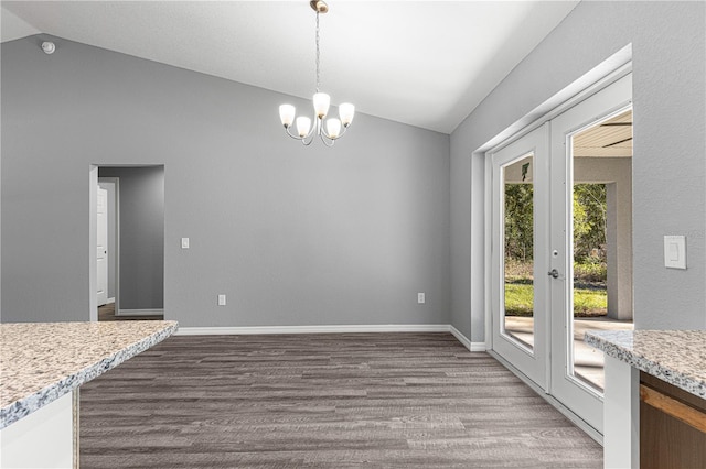 unfurnished dining area with vaulted ceiling, a notable chandelier, french doors, and hardwood / wood-style flooring