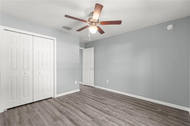 unfurnished bedroom featuring ceiling fan, a closet, and hardwood / wood-style flooring