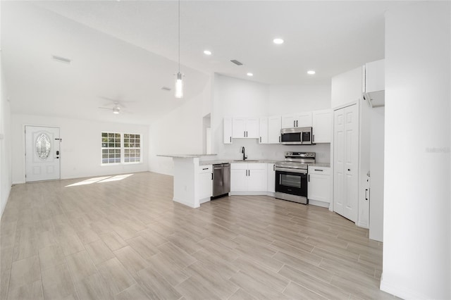 kitchen featuring sink, white cabinetry, hanging light fixtures, stainless steel appliances, and kitchen peninsula