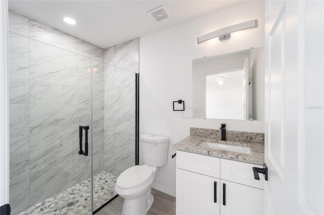 bathroom with vanity, hardwood / wood-style floors, a shower with door, and toilet