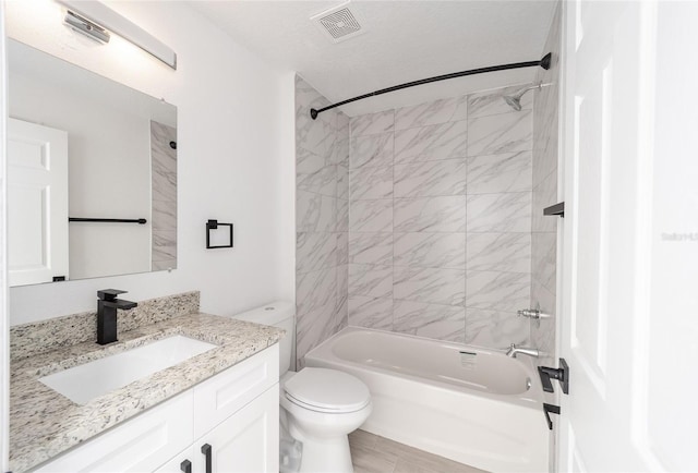 full bathroom with tiled shower / bath, vanity, a textured ceiling, and toilet